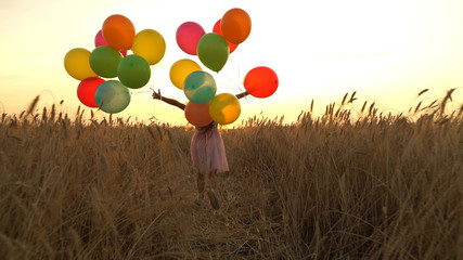 girl walking in a field with balloons