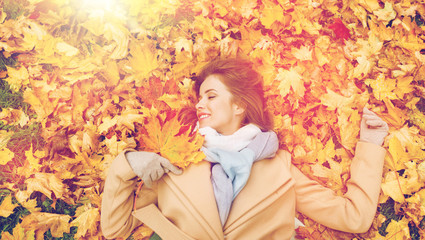 beautiful happy woman lying on autumn leaves