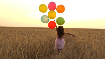 girl walking in a field with balloons