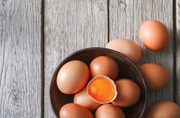 Fresh brown eggs in bowl on wood background