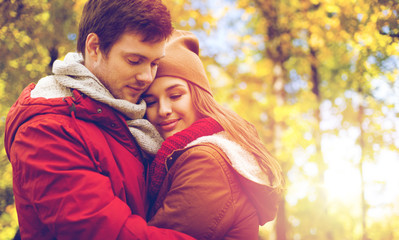 close up of happy couple hugging in autumn park