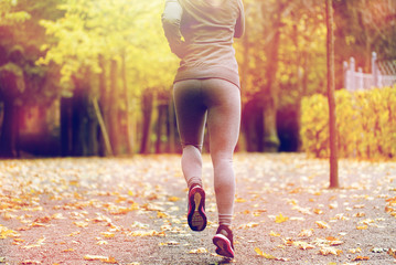 close up of young woman running in autumn park