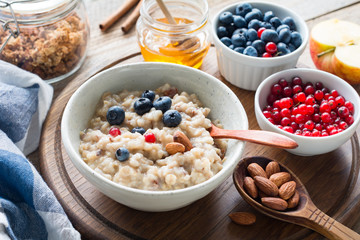 Oatmeal porridge with blueberries, almonds, cinnamon, honey, linseeds and red currants in bowl. Super food for healthy nutritious breakfast