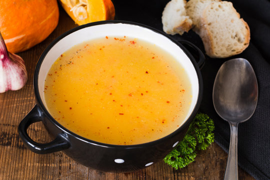 Pumpkin cream soup with red pepper flakes in bowl. Closeup view. Autumn comfort food