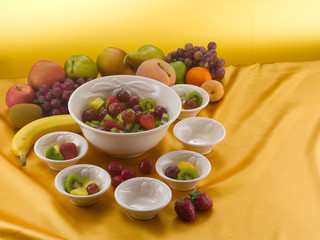 fruit salad served into white pocelain bowls on yellow background