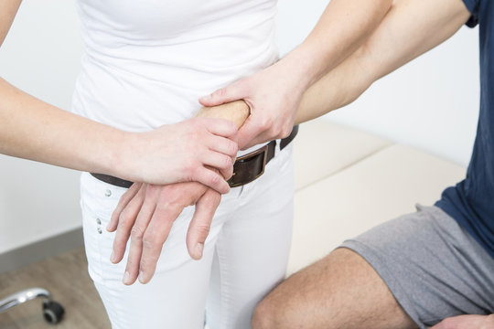 Physiotherapist supports man doing arm exercise