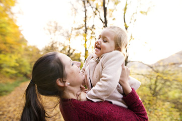 Mother and daughter on a walk in autumn forest.