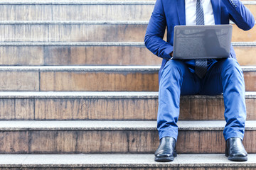 Businessman sitting on stairs and using laptop