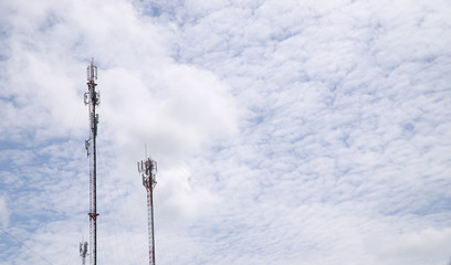 Mobile phone and communications tower with cloud and blue sky.