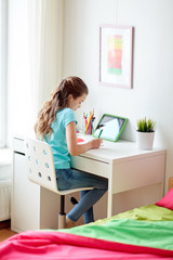 girl with tablet pc writing to notebook at home