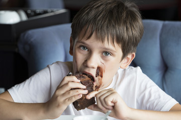 The boy is eating a large piece of cake in his hands 