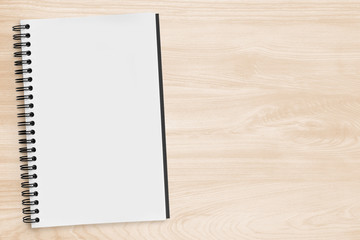 Blank notebook page is on top of wood office desk table. Top view with copy space, flat lay.