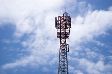 Mobile phone and communications tower with cloud and blue sky.