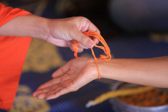 Sa&bull; Sin. Bracelet en coton symbolisant le lien sacr&eacute;. C&eacute;r&eacute;monie bouddhiste. Wat Simuong. Wat Si Muang. Vientiane. Laos.