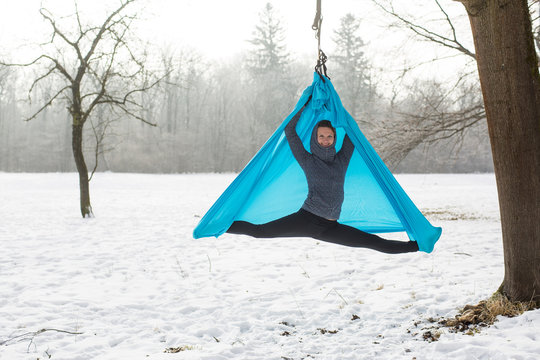 Young woman practicing aerial yoga outdoors