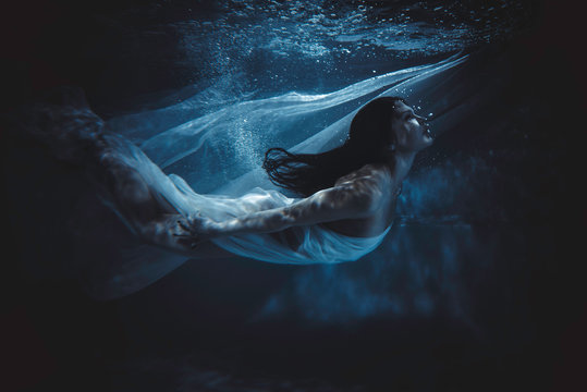 Beautiful woman swimming with fancy dress underwater