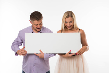 Young surprised couple portrait of a confident businessman showing presentation, pointing placard gray background. Ideal for banners, registration forms, presentation, landings, presenting concept.