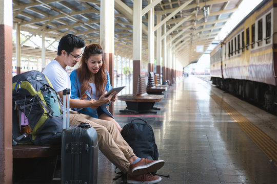 Couple traveler look at tablet at railway, train station