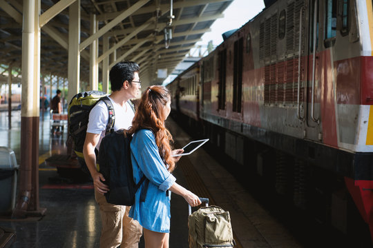 Couple traveler hold tablet look at the train