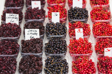 Dried cranberries, dried cherries, fresh red currants and fresh black currants on the market counter.