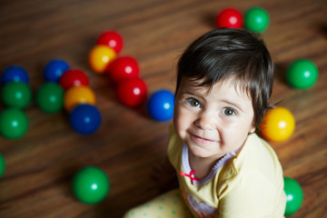 Fototapeta na wymiar Smiling little girl and colorful balls around/Smiling little girl and colorful balls around.