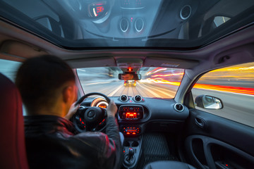 Urban high spees driving on a smal city car with panoramic roof. View from inside car natural light street and other cars is motion blurred.