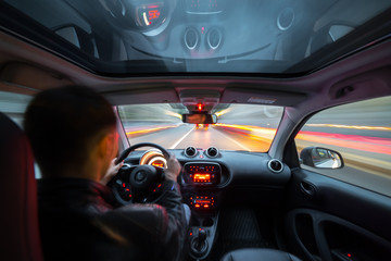 Urban high spees driving on a smal city car with panoramic roof. View from inside car natural light street and other cars is motion blurred.