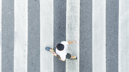 the top view of man walk across the pedestrian crosswalk in white and grey pattern