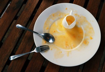 Empty white plate with fork and spoon after finish eating Dessert on wooded table