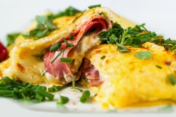 Poster Fluffy stuffed egg omelette with ham, cheese and green herb, closeup. © slunicko24