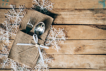 christmas table place setting and silverware, snowflakes on wooden background with space.