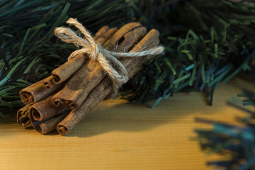 Fototapeta na wymiar Bundle of cinnamon and green branches on wooden background. Christmas decoration.