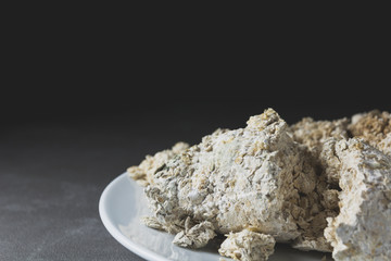 Mold growing rapidly on moldy bread in white spores. Close up stack of moldy bread on white plate.