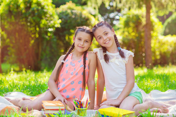 Two pretty little girls reading in park