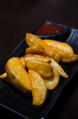 sweet potato fries with ketchup on black  plate over old wooden table.