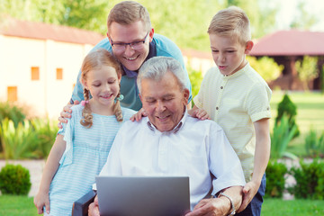 Happy family with grandfather during internet talking on laptop