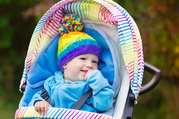 Baby boy in stroller in autumn park