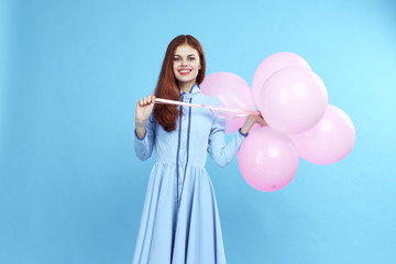 young woman with long hair holds a bunch of balloons