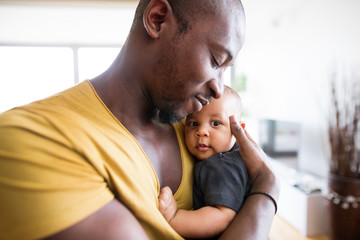 Young afro-american father holding his baby son in the arms