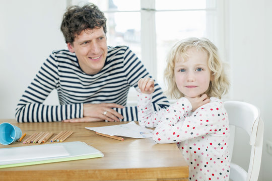 Father and daughter coloring a book