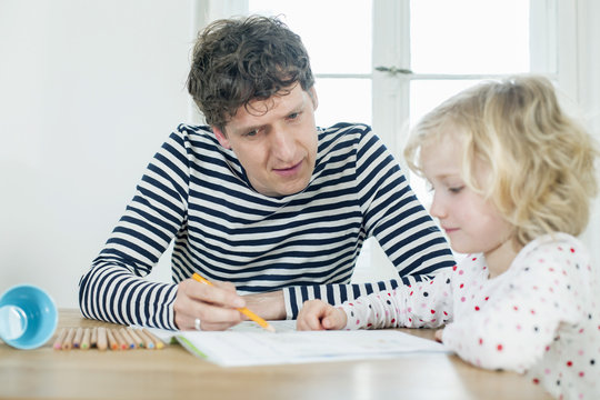 Father and daughter coloring a book