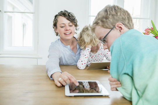 Mother and children playing with digital tablet