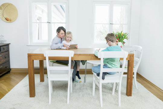 Mother and two children with digital tablet in living room