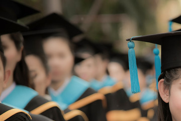 Graduates in commencement graduation ceremony row, metaphor education, success, concept, background with copy space, selective focus on graduation cap