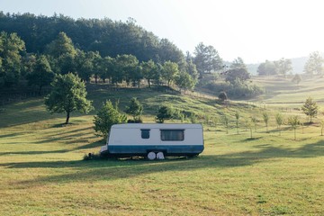 Vintage antique american camper rv van parked on side of grassy hill or mountain with beautiful...