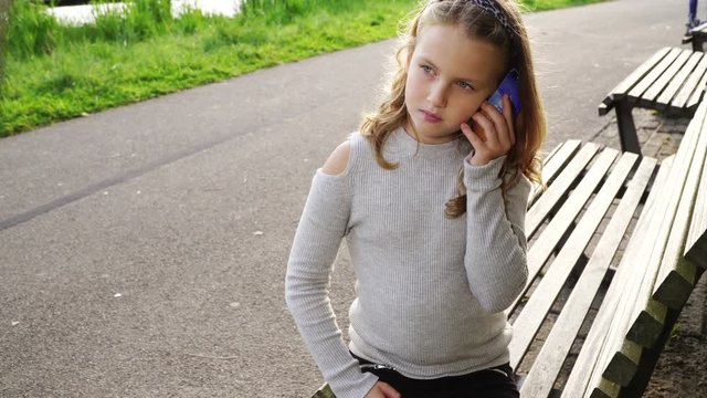 Happy girl in park playing on smartphone 
