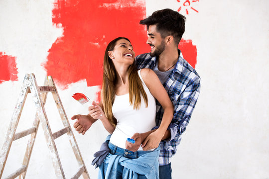 Young happy couple painting walls in their new house