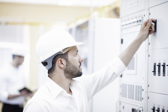 Two engineers checking switch in electricity substation
