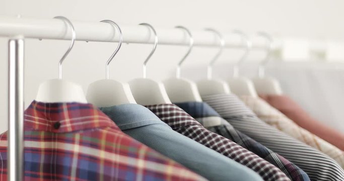 Fashionable men's shirts hang on hangers.