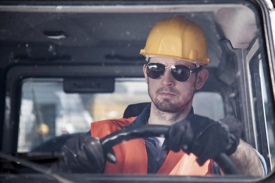 Engineer with hardhat and sunglasses driving car